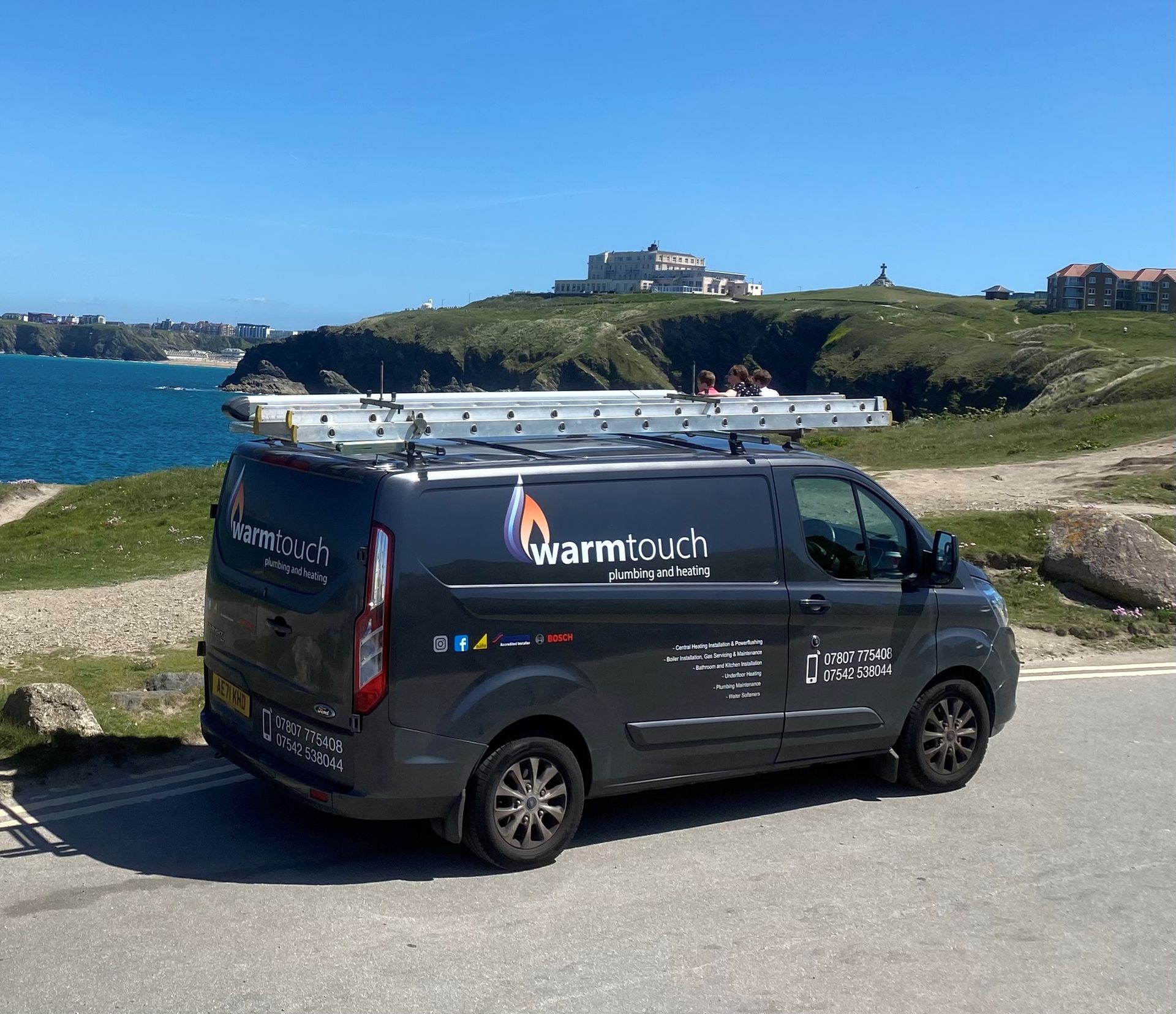 Warmtouch Plumbing and Heating van with roof ladder parked on a coastal headland